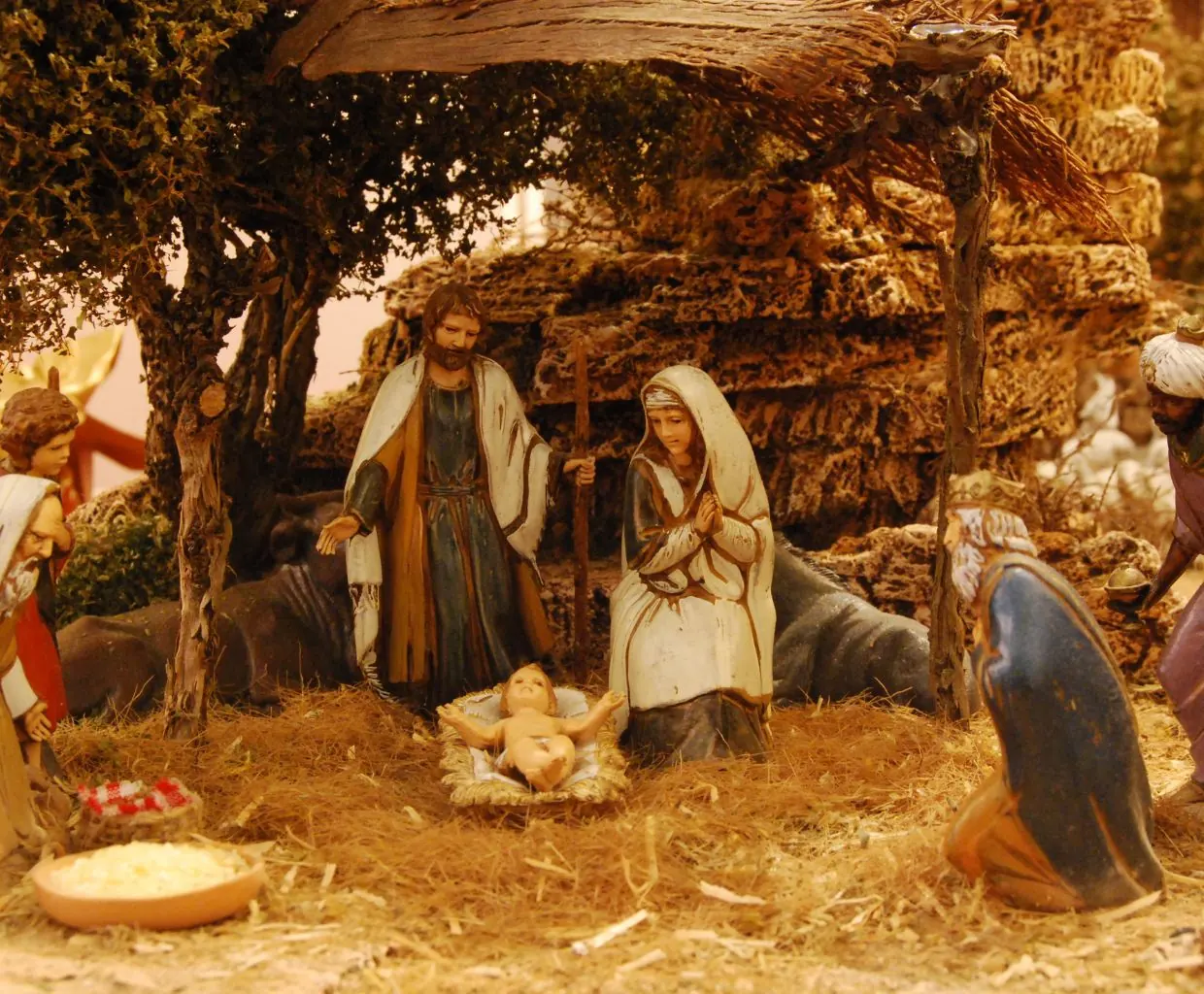 Figuras del belén de Navidad, con María, José y el Niño Jesús en un establo rústico iluminado con luz cálida
