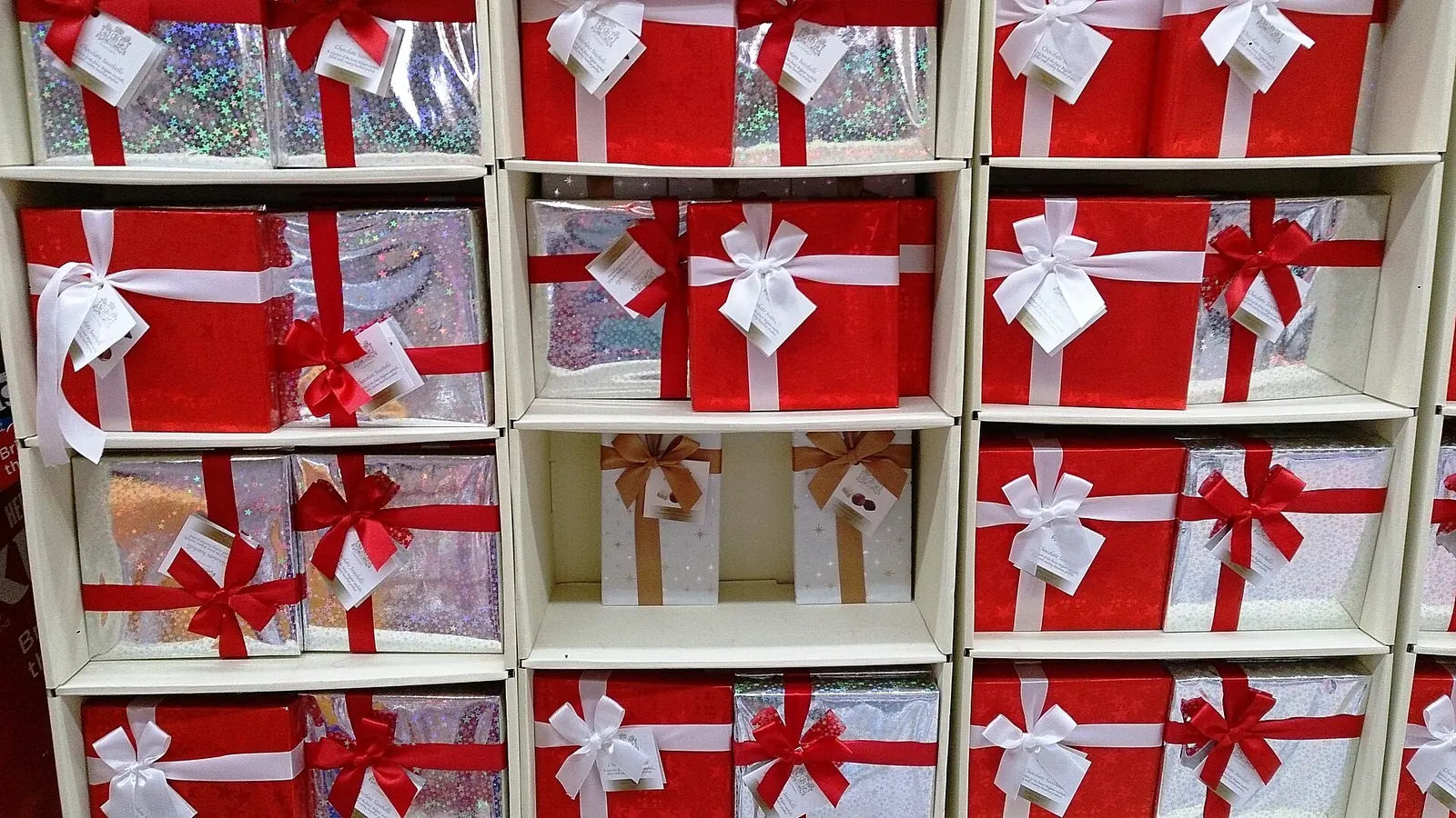Estanterías de una tienda llenas de cajas de regalo rojas y plateadas con lazos y etiquetas