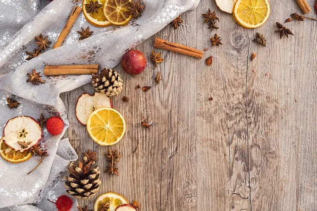 Mesa de madera rústica con rodajas de naranja seca, canela en rama, anís estrellado, piñas y bayas rojas