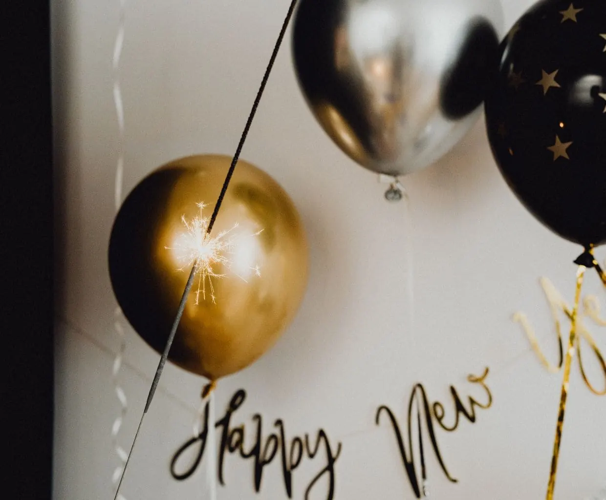 Globos dorados y negros con letras de Happy New Year para celebrar el Año Nuevo