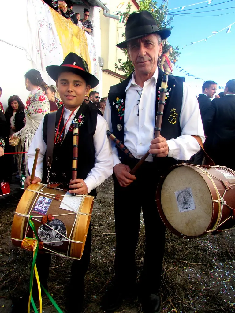 Un niño y un hombre con trajes tradicionales tocando tambores en una fiesta popular