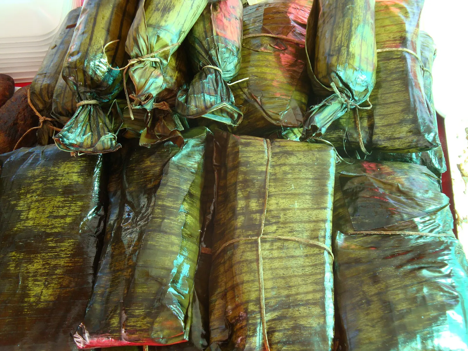 Tamales envueltos en hoja de plátano y atados con cordel, apilados unos sobre otros
