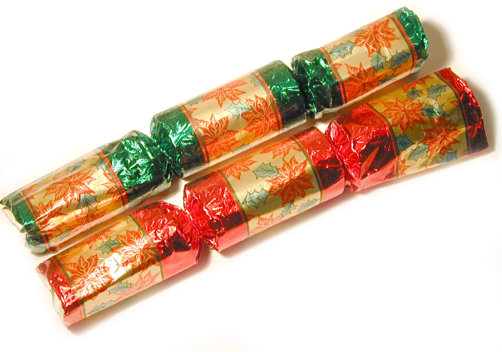 Dos crackers navideños envueltos en papel brillante rojo, verde y dorado con flores de Pascua