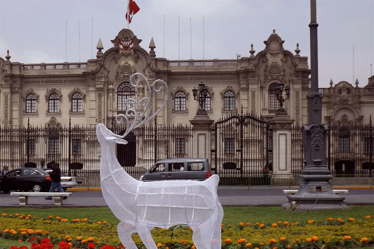 Reno navideño de luces blancas entre flores rojas frente al Palacio de Gobierno, en la Plaza de Armas de Lima