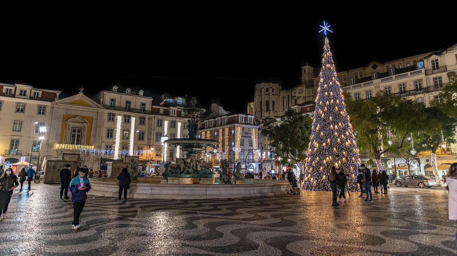 Gran árbol de Navidad iluminado en la plaza del Rossio de Lisboa de noche, con su suelo de adoquines ondulados