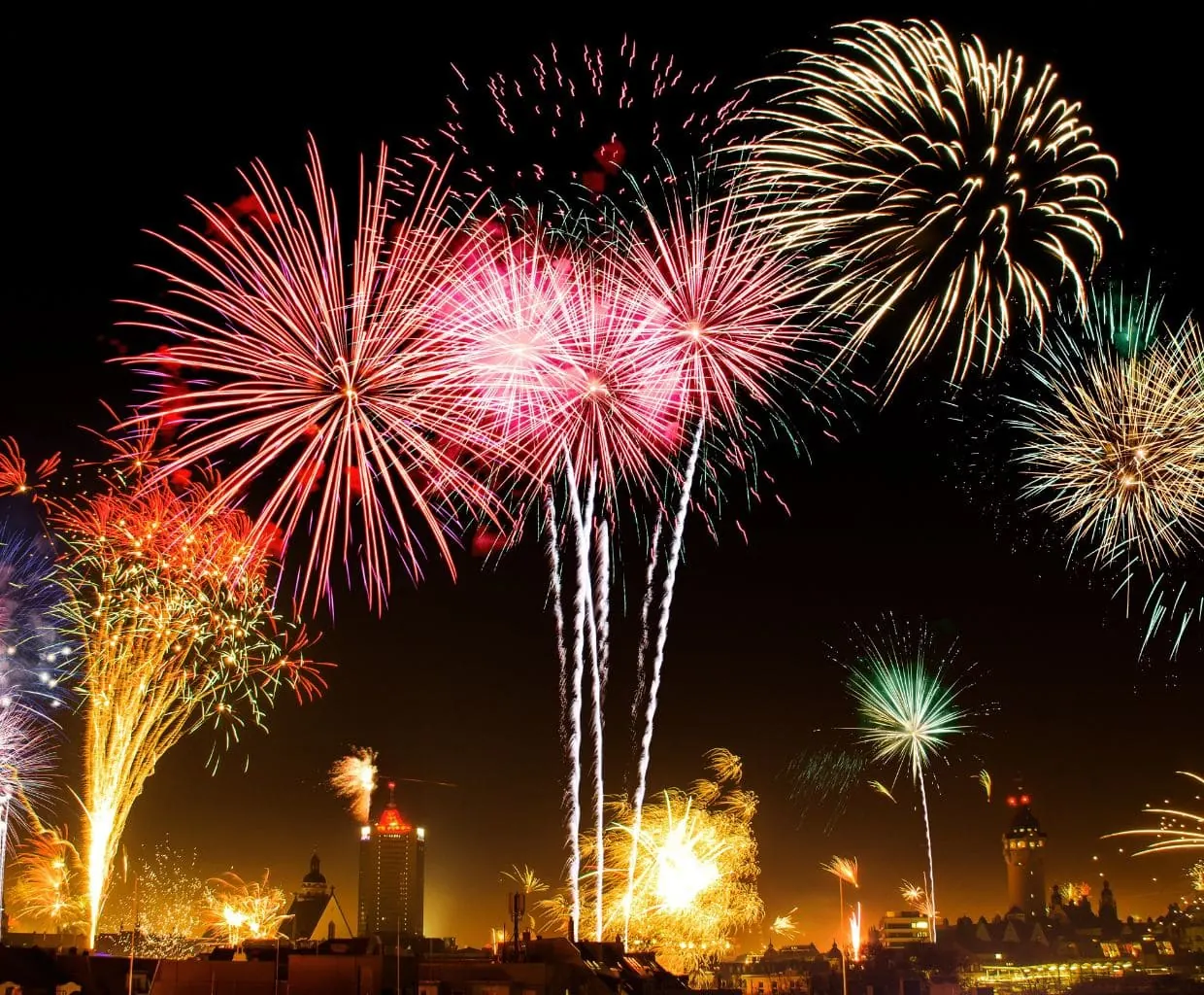 Fuegos artificiales de colores iluminando el cielo nocturno de una ciudad