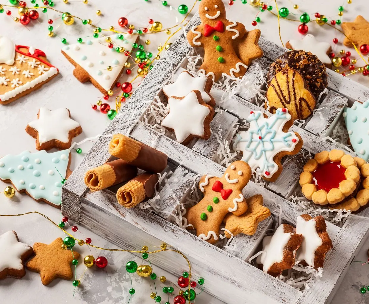 Caja de madera con galletas navideñas variadas: muñecos de jengibre, estrellas y galletas rellenas de mermelada