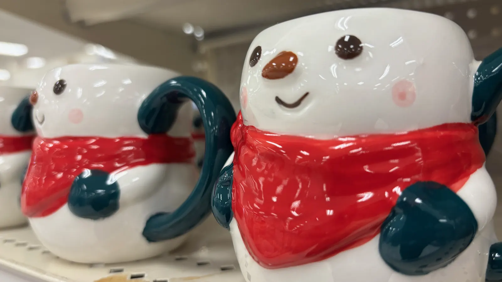 Tazas de cerámica con forma de muñeco de nieve con bufanda roja en una estantería