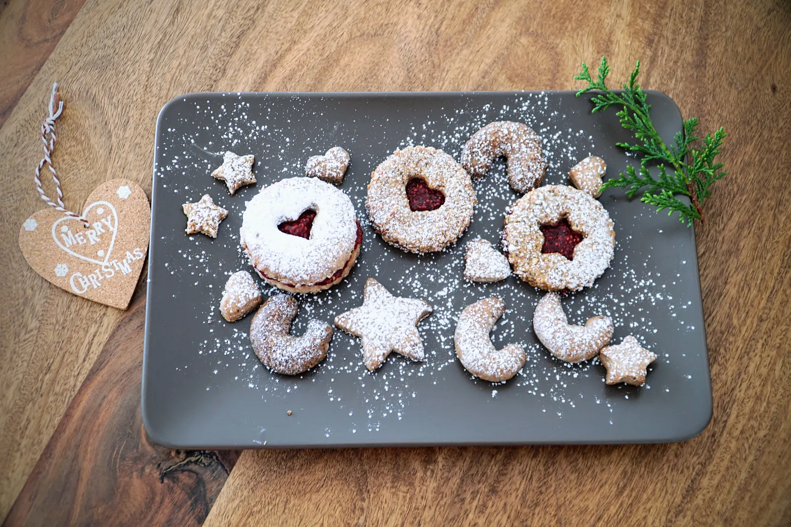 Galletas navideñas con azúcar glas en una bandeja, junto a una etiqueta de corcho con forma de corazón