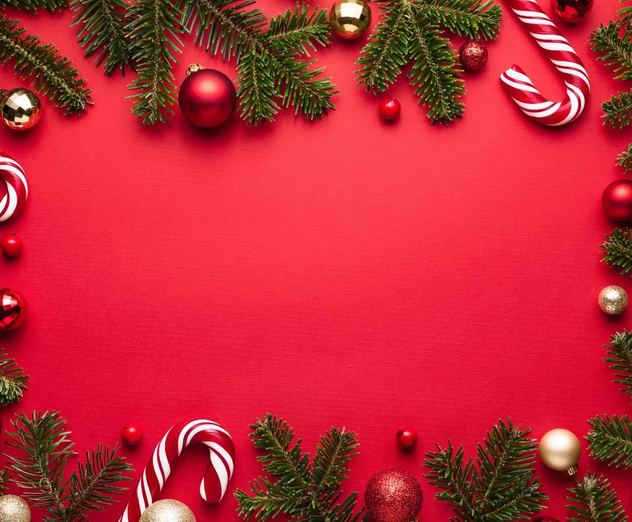 Fondo rojo enmarcado por bastones de caramelo, bolas de Navidad y ramas de abeto alrededor de un espacio vacío